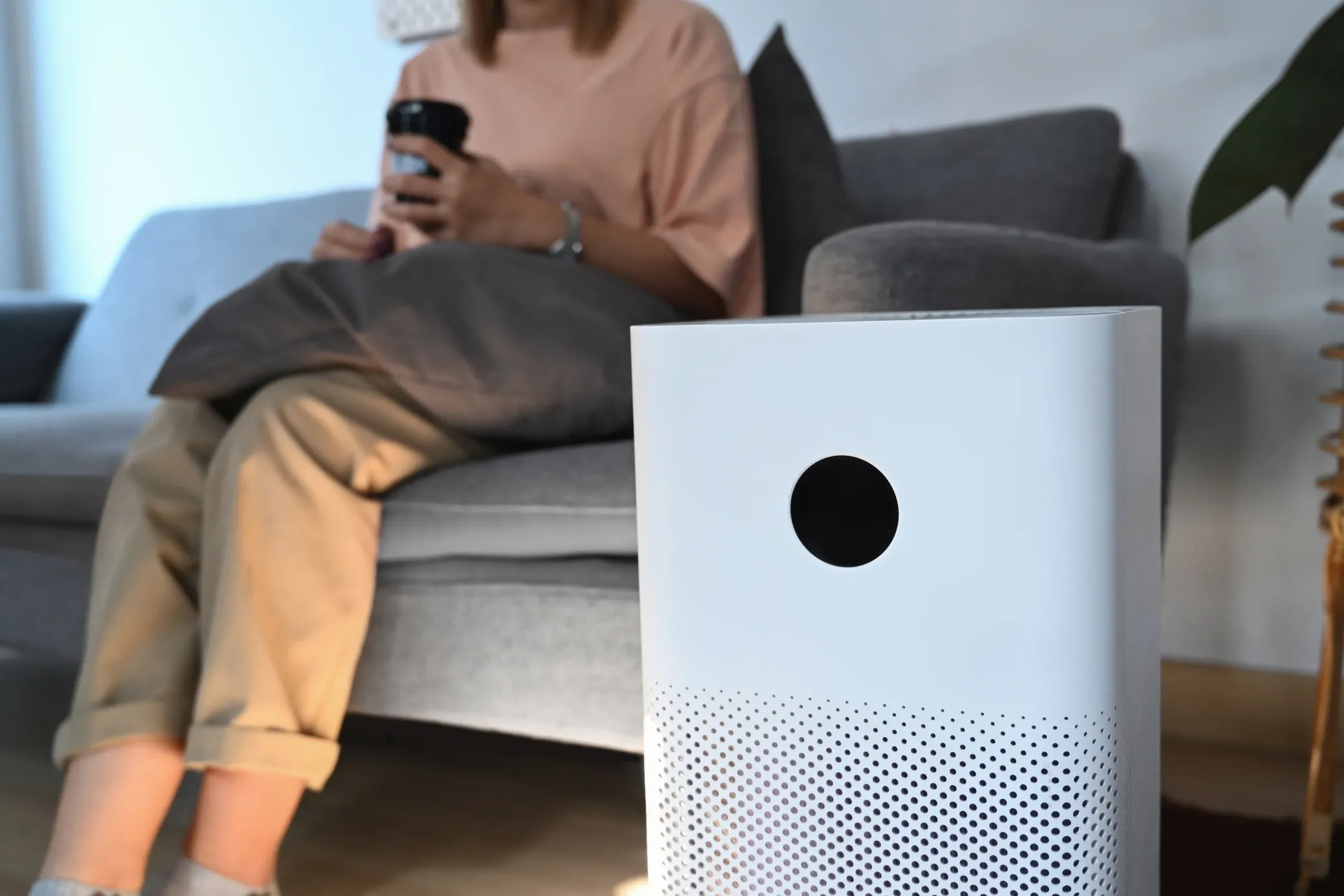 Air purifier in a well-lit living room effectively filtering and cleaning the air, removing dust particles and PM2.5 pollutants
