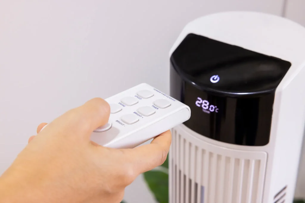 Close-up of Asian woman's hand pressing a button on a remote control for an air purifier in a bedroom 