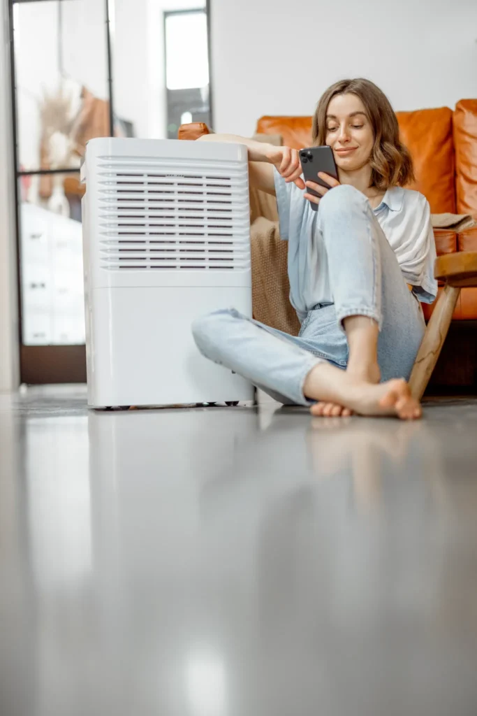 Woman sitting near an air purifier and moisturizer appliance