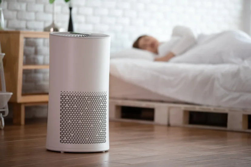 Woman sleeping in a cozy white bedroom with an air purifier for filtering and cleaning the air, removing dust and PM2.5 particles using HEPA technology, promoting fresh air and a healthy life